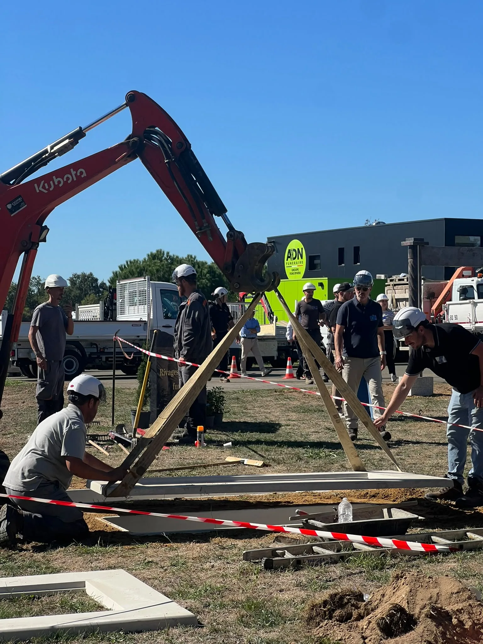 Engin de levage et marbriers en exercice au cimetière pédagogique